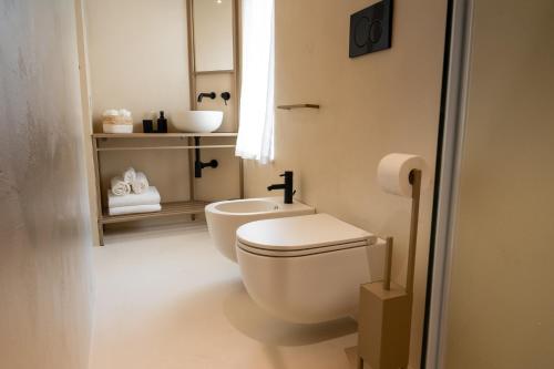 a white bathroom with a toilet and a sink at NEW OPENING - Palazzo Gasparino Suites in Monopoli