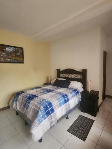 Un dormitorio con una cama con una manta azul y blanca. en Villa Alissa, en Quetzaltenango