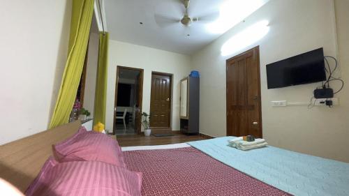 a bedroom with a bed and a flat screen tv at Alchemist Villa-Kazhakootam in Trivandrum