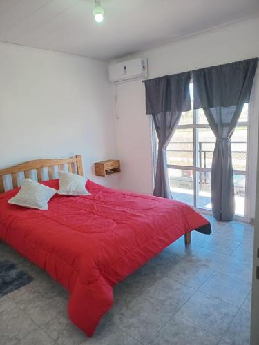 a red bed in a room with a window at Departamentos Los dos Pinos in San José