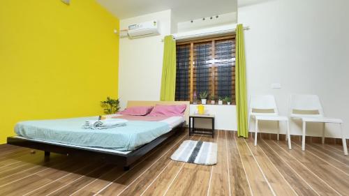 a bedroom with a bed and a yellow wall at Alchemist Villa-Kazhakootam in Trivandrum