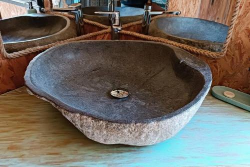 a stone sink in a bathroom with two mirrors at Terres D'Éden, Le Gîte de Charme in Saint-Joseph