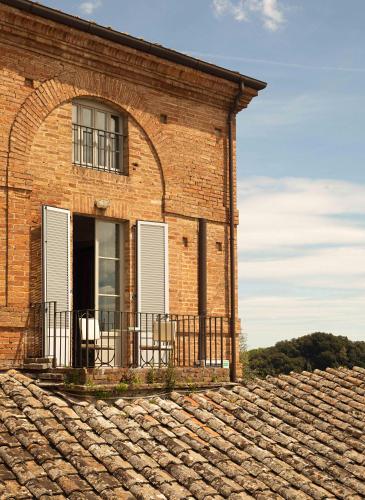 a brick building with a balcony on top of a roof at Hotel Certosa Di Maggiano in Siena