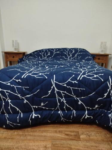a bed with a blue comforter with branches on it at Apartamento centro young in Young