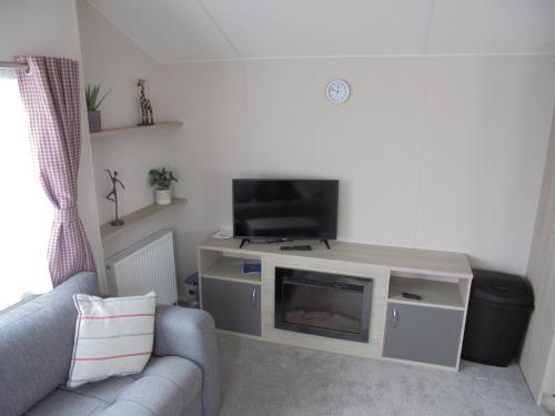 a living room with a couch and a flat screen tv at Kingfisher Festival 6 Berth Central Heated Close to site entrance in Ingoldmells