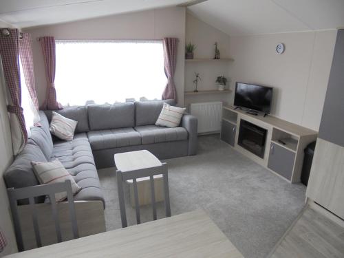a living room with a couch and a tv at Kingfisher Festival 6 Berth Central Heated Close to site entrance in Ingoldmells