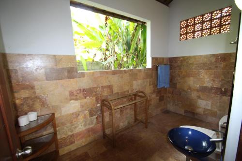 a bathroom with a toilet and a window at Uma Capung Mas Cottage in Ubud