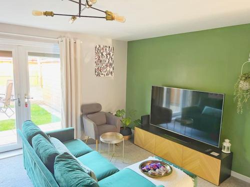 a living room with a blue couch and a flat screen tv at Comfy Modern 3BR Semi Detached 400Mb Wifi Free Double Parking in Kenton
