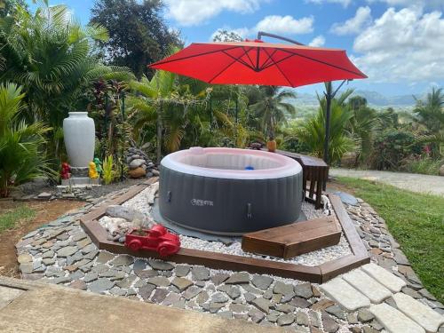a hot tub with a red umbrella in a yard at Bungalow Cactus in Le François