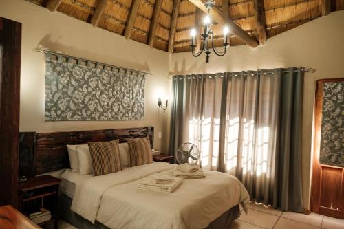 a bedroom with a bed and a large window at La La Nathi Country Guesthouse in Harrismith