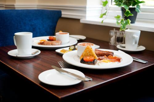 a wooden table with plates of breakfast food on it at Basingstoke Country Hotel & Spa in Hook