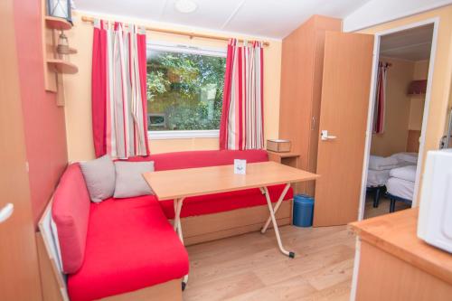 un salon avec un canapé rouge et une table dans l'établissement Camping Onlycamp La Colombière, à Pesmes
