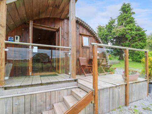 a wooden cabin with a porch and a chair on a deck at Oak View in Llangadog