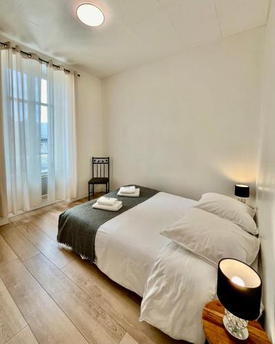 une chambre avec un grand lit blanc et une fenêtre dans l'établissement Appartement T2 Place Carnot -DABNB, à Limoges