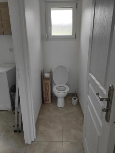 a white bathroom with a toilet and a window at Chez CHARLETTE in Les Malots