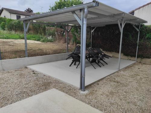 a pergola with chairs under it in a yard at Chez CHARLETTE in Les Malots