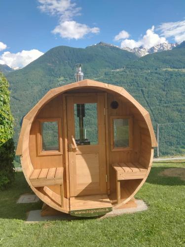 a wooden iguana cabin with mountains in the background at Il posto al sole in Teglio