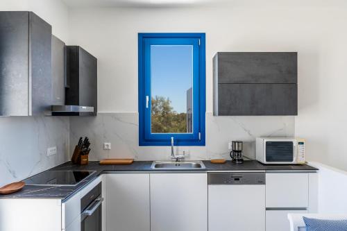 a kitchen with a sink and a blue window at Seaside Serenity House in Monolithos