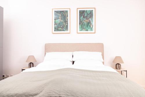 1 dormitorio con 1 cama blanca y 2 cuadros en la pared en Design Suite! Familie - Küche - Zentral, en Wuppertal