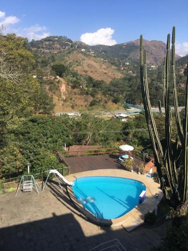 a large blue swimming pool next to a cactus at Varanda Itaipava! in Petrópolis