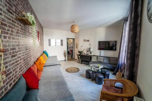un salon avec un canapé et un mur de briques dans l'établissement Double Appart Hypercentre Blois à 5 min Château, à Blois