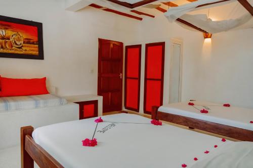 two beds in a room with red and white at Baobab Village in Watamu