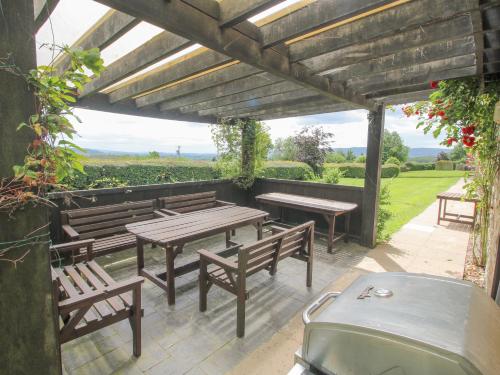 a patio with benches and tables and a grill at The Park in Craven Arms