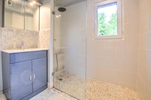a bathroom with a sink and a glass shower at Le Chalet du Manoire in Saint-Laurent-sur-Manoire
