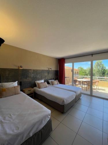 a hotel room with two beds and a balcony at Hôtel Le Maritime in Argelès-sur-Mer