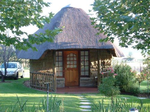 a small house with a thatch roof at La La Nathi Country Guesthouse in Harrismith