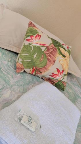 a pillow on top of a bed with a flower pattern at Pousada Sonho in Apucarana