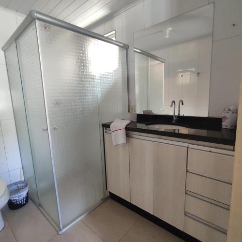 a bathroom with a glass shower and a sink at Pousada Sonho in Apucarana