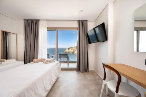アギア・ペラギアにあるAthina Palace Resort & Spaのベッドと机とテレビがあるホテルの部屋