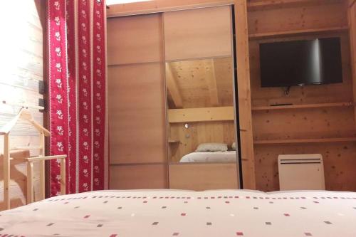 une chambre avec un placard à miroir avec une télévision et un lit dans l'établissement Appartement sur les pistes de Megève, à Megève