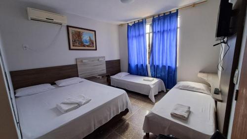 a hotel room with two beds and a television at Hotel Blue Star II in Foz do Iguaçu