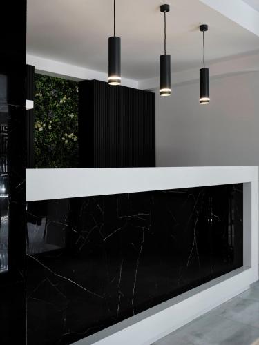 a black and white reception counter with three pendant lights at AVA Hotel & Residences Athens Riviera in Athens