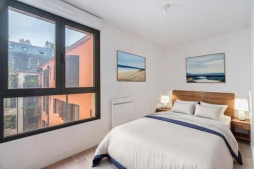 une chambre avec un lit et une grande fenêtre dans l'établissement Charmant Appartement Montmartre, à Paris