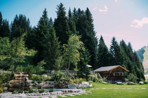 a garden with a house and trees in the background at Berghotel Hochfügen in Hochfugen