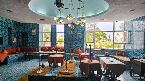 a restaurant with blue tiled walls and tables and windows at Monarque El Fatimi Mahdia in Mahdia