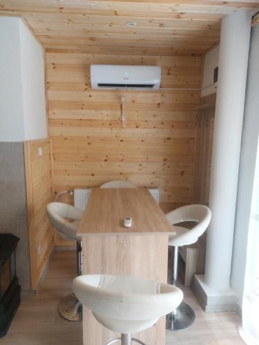 a table and chairs in a room with wooden walls at Oázis Vendégház és Appartman in Szilvásvárad