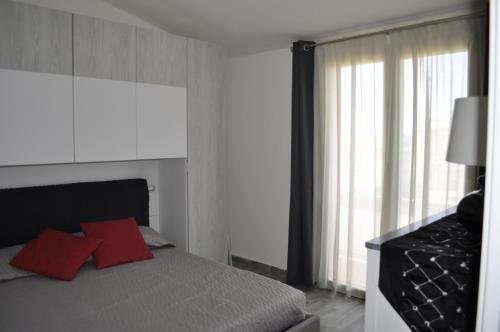 une chambre avec un lit avec des oreillers rouges et une fenêtre dans l'établissement Residenza Benvenuto Cellini, à La Maddalena