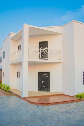 a white house with a balcony on the side at Pot of Gold East Legon in Accra