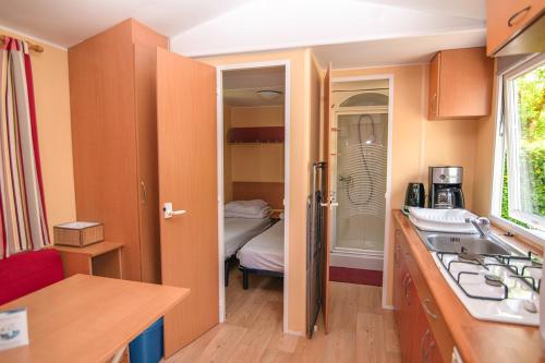 Il comprend une chambre et une petite cuisine avec un évier. dans l'établissement Camping Onlycamp La Colombière, à Pesmes