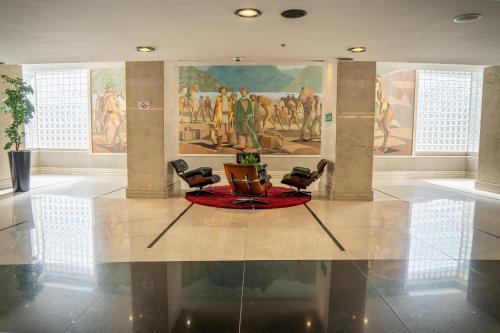 a lobby with chairs and a painting on the wall at Hotel Nacional Inn Jaragua Sao Paulo in Sao Paulo