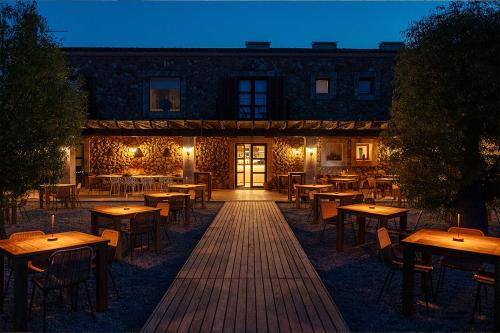 a restaurant with wooden tables and chairs in front of a building at La Farm Baleares in Santa Maria del Camí