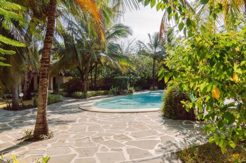 a swimming pool in a yard with palm trees at Baobab Village in Watamu