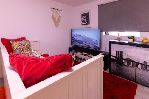 a living room with a red chair and a tv at Yellow House - EcoHost - Casa com jardim privado e BBQ perto do Porto, aeroporto e praias in Perafita