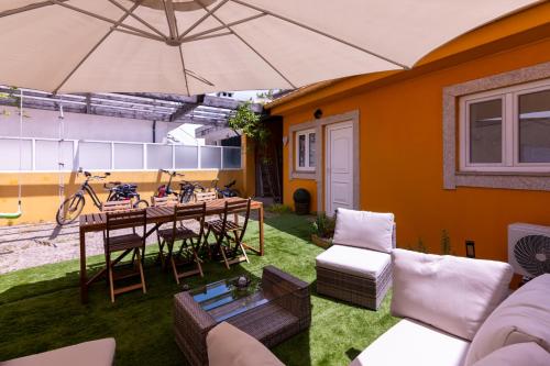 a patio with a table and chairs and an umbrella at Yellow House - EcoHost - Casa com jardim privado e BBQ perto do Porto, aeroporto e praias in Perafita