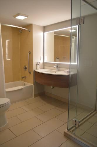 a bathroom with a sink and a shower and a toilet at Holiday Inn & Suites Montreal Airport by IHG in Dorval