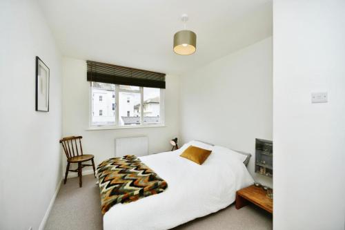 a white bedroom with a bed and a chair at Sunny Seaside Sanctuary - Two Bedroom Apartment in Brighton & Hove